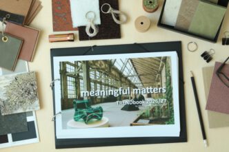 „TRENDbook 2026/27 mit dem Titel ‚meaningful matters‘, auf einem Tisch liegend umgeben von Materialmustern und Design-Utensilien.