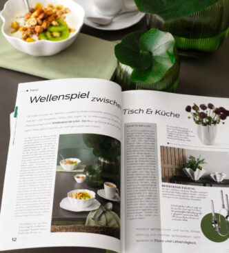 zu sehen ist die aufgeschlagene Zeitschrift mit dem Artikel auf einem Tisch liegend mit gewelltem Porzellan